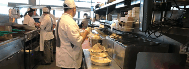cooks in kitchen prepping plates